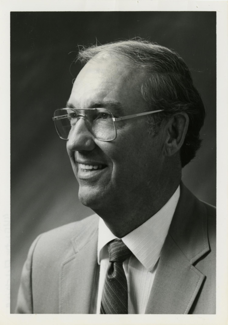 Jesse Fletcher pictured in suit and tie, from the side while smiling