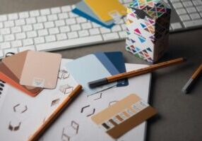 a desk with a keyboard, pencils, and various color samples